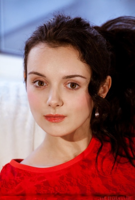 Dark-haired teen with long legs gets completely naked on a couch by herself