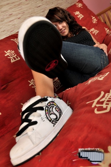 Sweet young girl Andi Land exposes her tiny tits and slit on a bed in sneakers