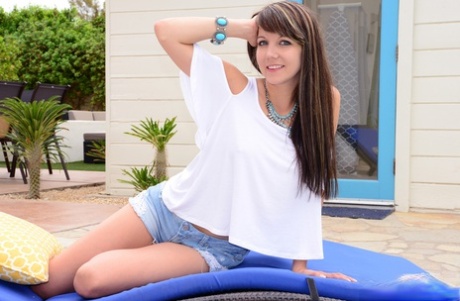 Nice young girl Andi Land uncovers her small tits on a patio