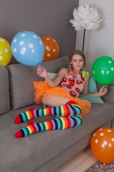 Skinny teen Lili removes her clothes and long socks to pose nude amid balloons
