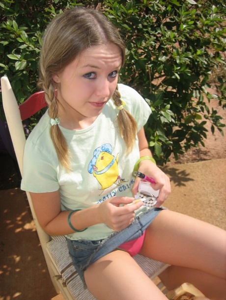 Young girl smokes a cigarette while exposing her tits and pussy