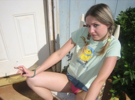 Young girl smokes a cigarette while exposing her tits and pussy