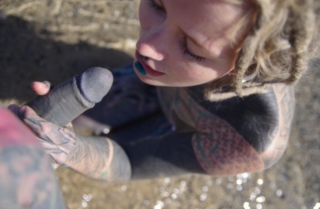 Tattooed girl jerks and sucks a tattooed penis near the ocean
