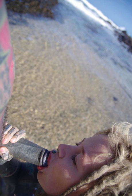 Tattooed girl jerks and sucks a tattooed penis near the ocean