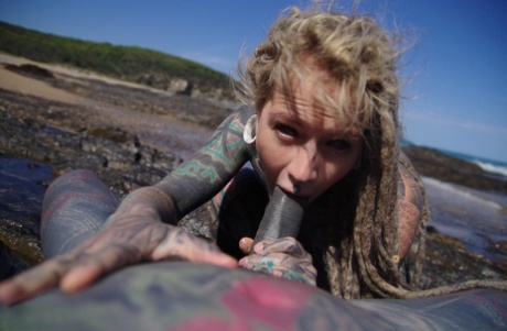 Tattooed girl jerks and sucks a tattooed penis near the ocean