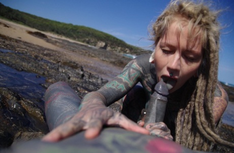 Tattooed girl jerks and sucks a tattooed penis near the ocean