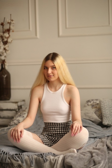 Young blonde beauty Suna slowly removes her clothing on top of her bed