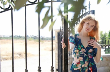 Sweet teen Alice May takes off her robe to go nude upon a garden wall