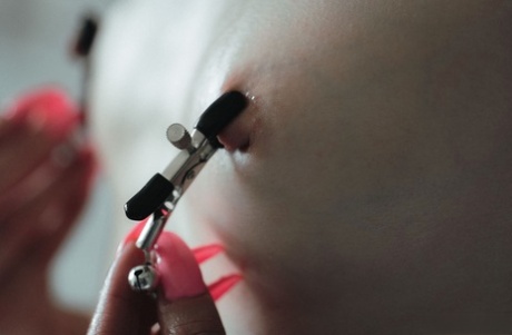Tattooed brunette Pollie Starr attaches nipple clamps while bathing