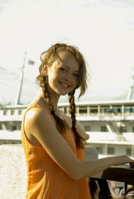 Charming teen Vega tugs on her pigtails before going nude next to the water