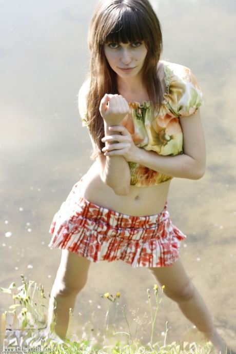 Beautiful teen Lena exposes her pert tits and bald cunt by the lake