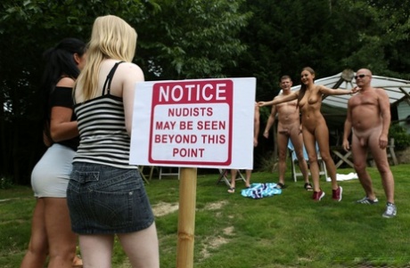 Lovely clothed female students blow off a nudist colony outdoors