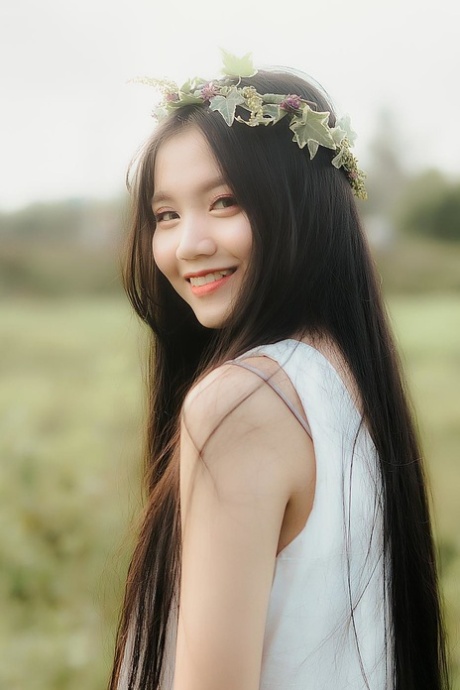Great looking Asian girl posing in her white dress in beautiful nature