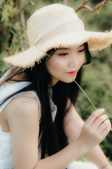 Great looking Asian girl posing in her white dress in beautiful nature
