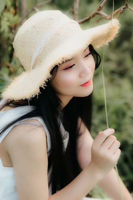 Great looking Asian girl posing in her white dress in beautiful nature