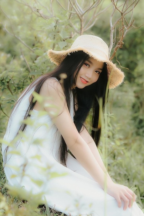 Great looking Asian girl posing in her white dress in beautiful nature