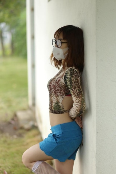 Asian brunette babe with a mask & glasses poses in her sexy outfit
