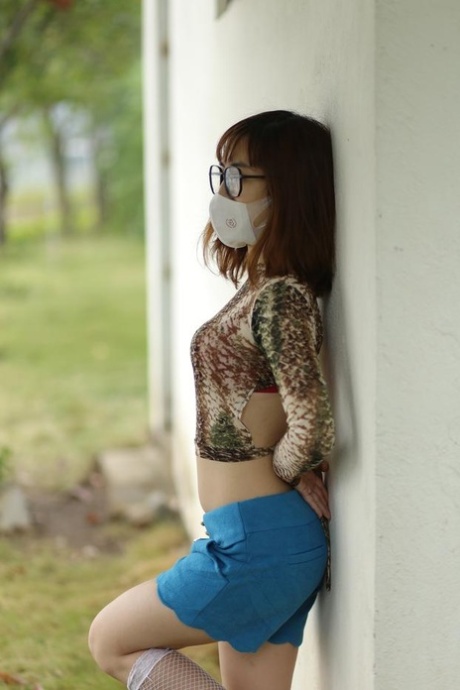 Asian brunette babe with a mask & glasses poses in her sexy outfit