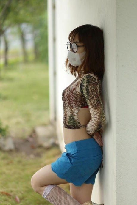 Asian brunette babe with a mask & glasses poses in her sexy outfit