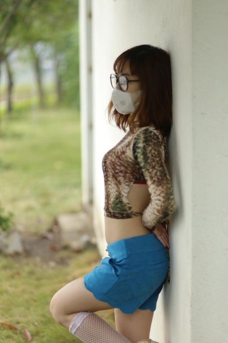 Asian brunette babe with a mask & glasses poses in her sexy outfit