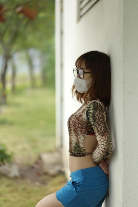 Asian brunette babe with a mask & glasses poses in her sexy outfit